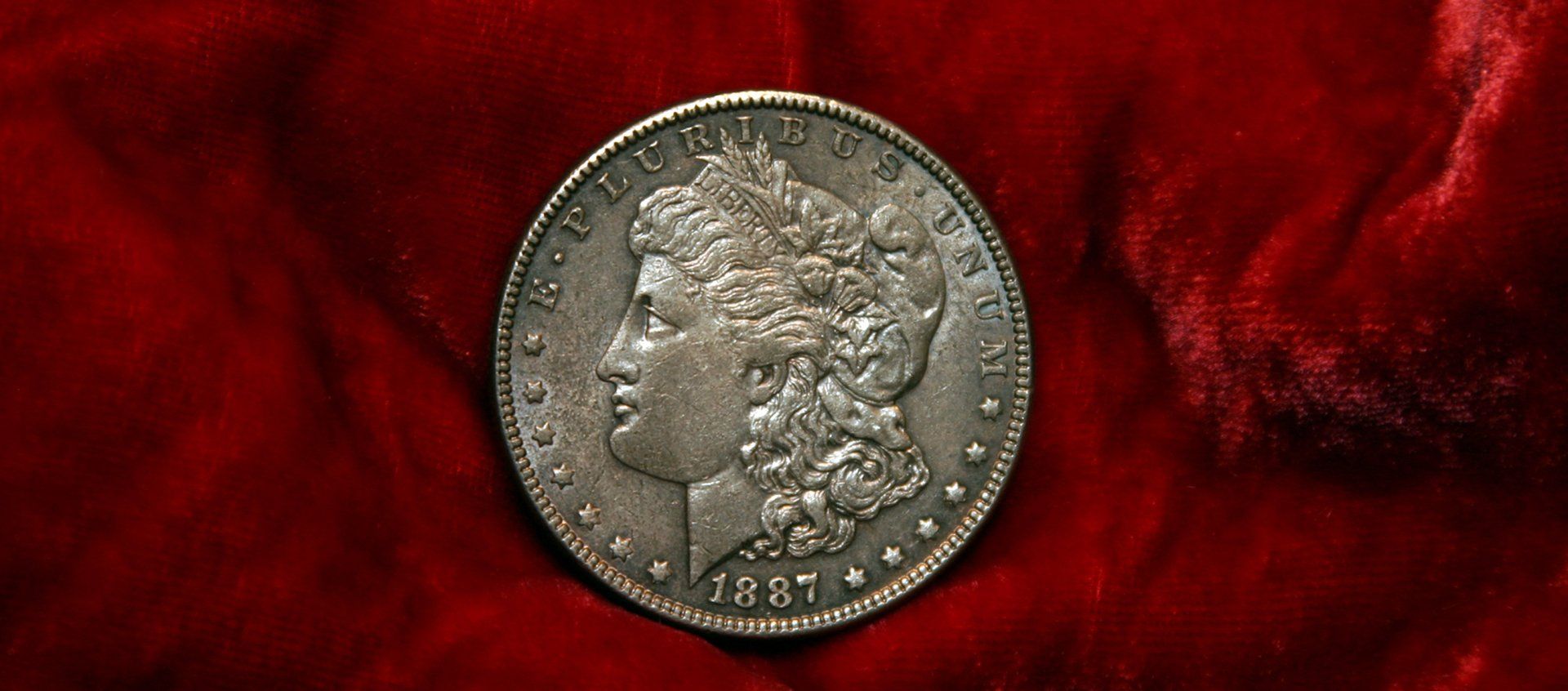 1887 Morgan silver dollar on red fabric