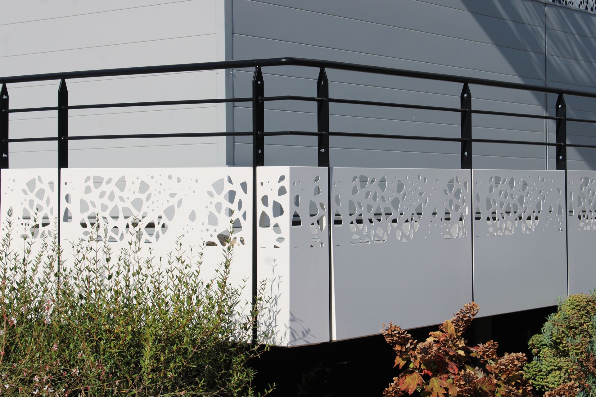 Un balcon avec une balustrade noire et un mur blanc