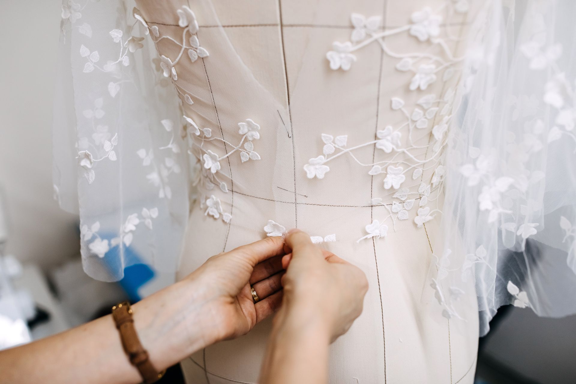 A person is working on a wedding dress on a mannequin.