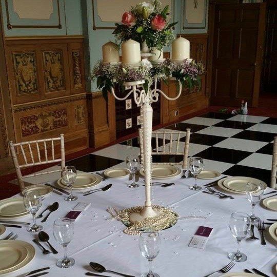 A table set for a wedding reception with a candelabra filled with candles and flowers