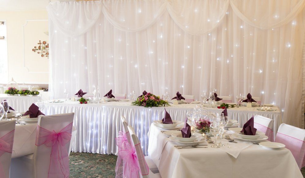 A room with tables and chairs set up for a wedding reception.