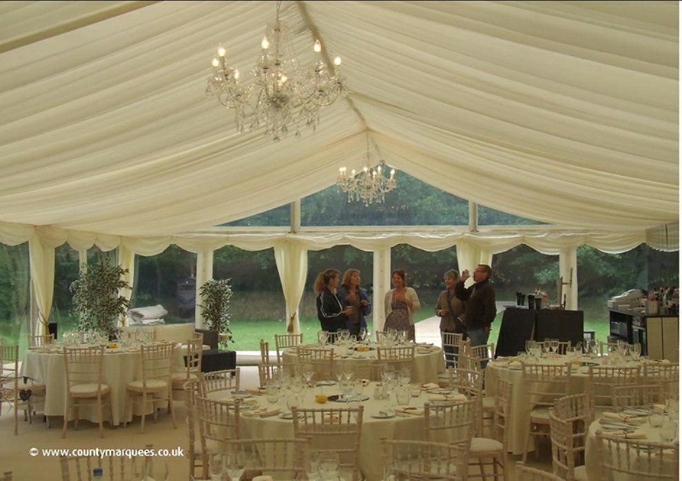 A large white tent with tables and chairs and a chandelier