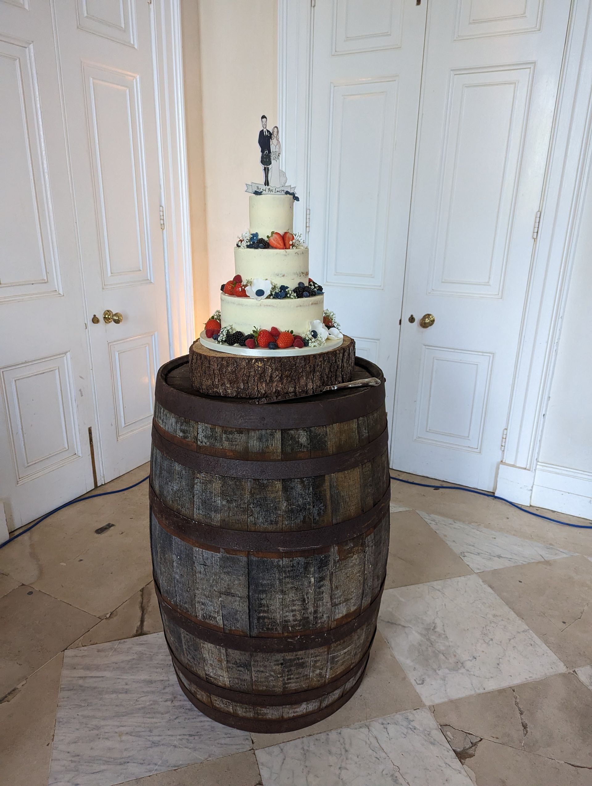 A wedding cake is sitting on top of a wooden barrel.