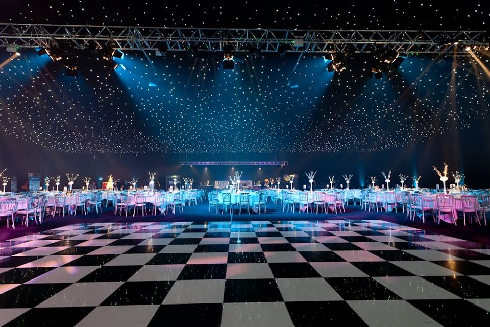 A black and white checkered dance floor with tables and chairs in the background.