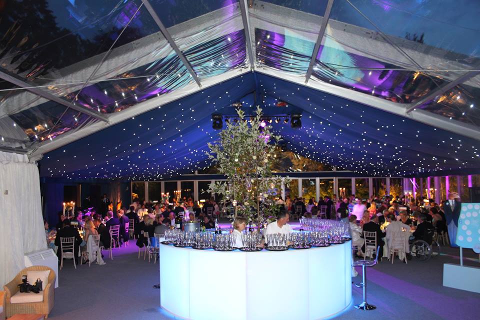 A large room with tables and chairs under a clear tent.
