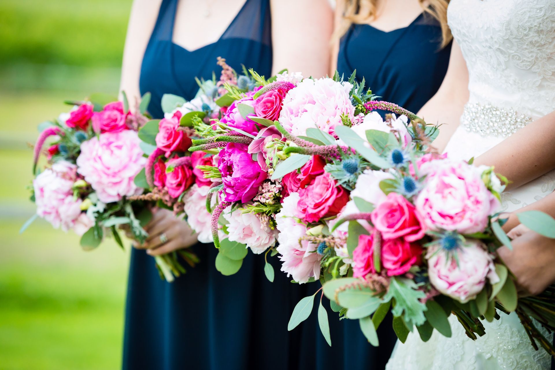 A bride and her bridesmaids are holding bouquets of pink flowers.