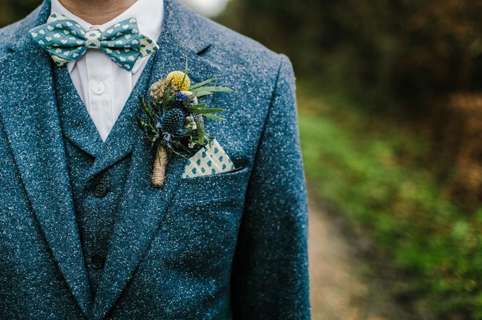 The groom is wearing a blue suit and a green bow tie.