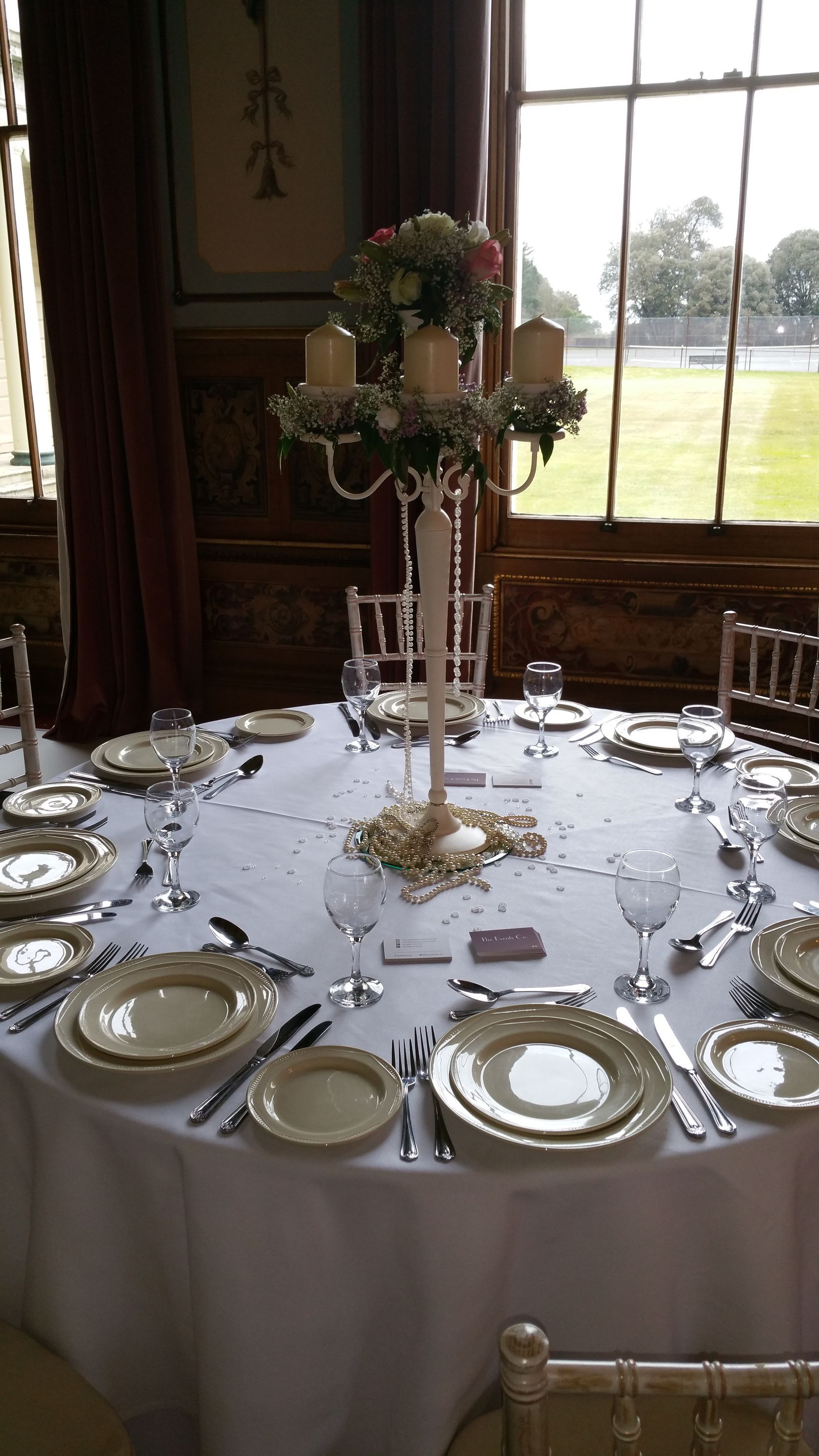 A table set for a wedding reception with plates , utensils , and candles.