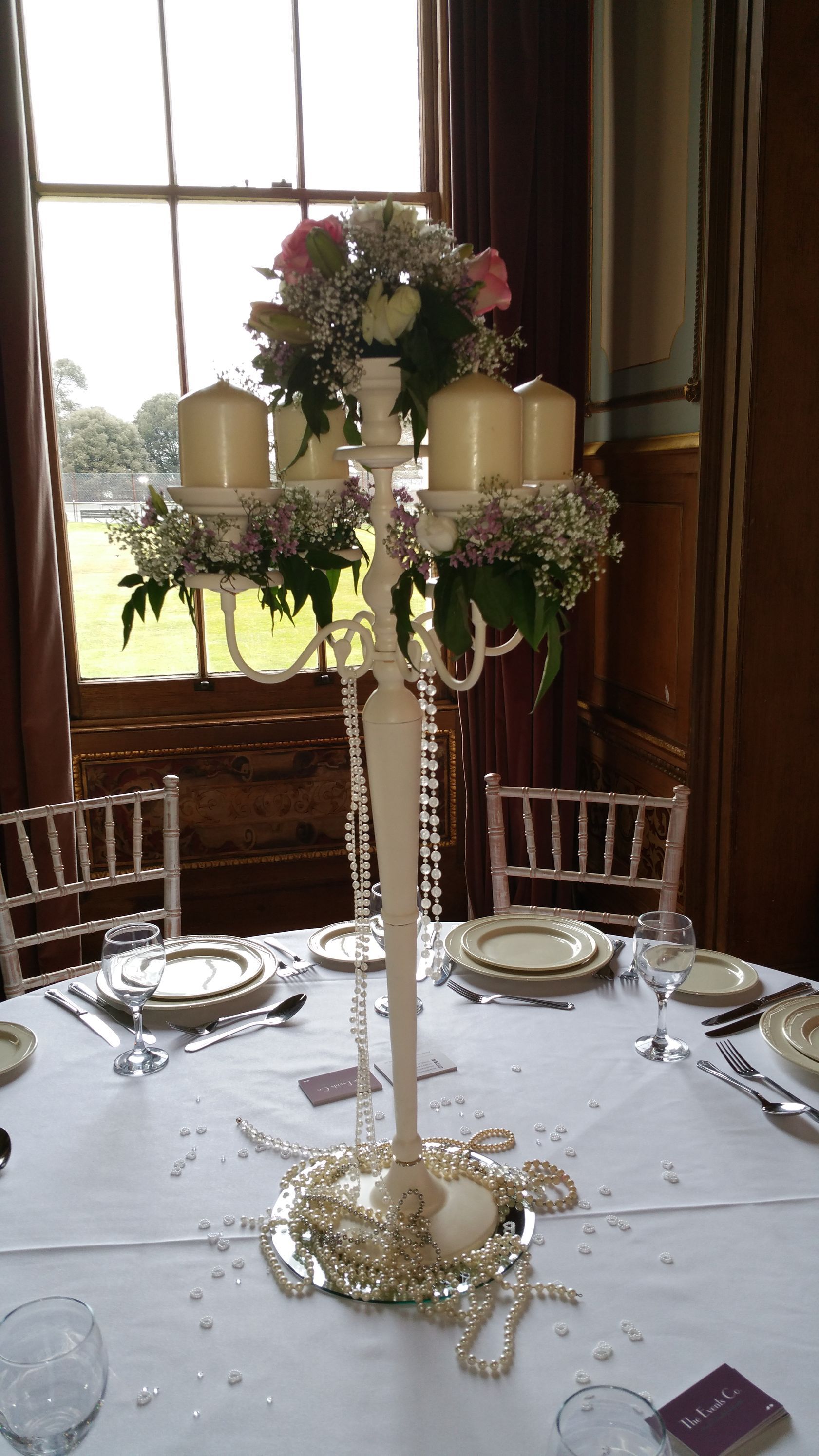 A candelabra with candles and flowers on it is on a table.