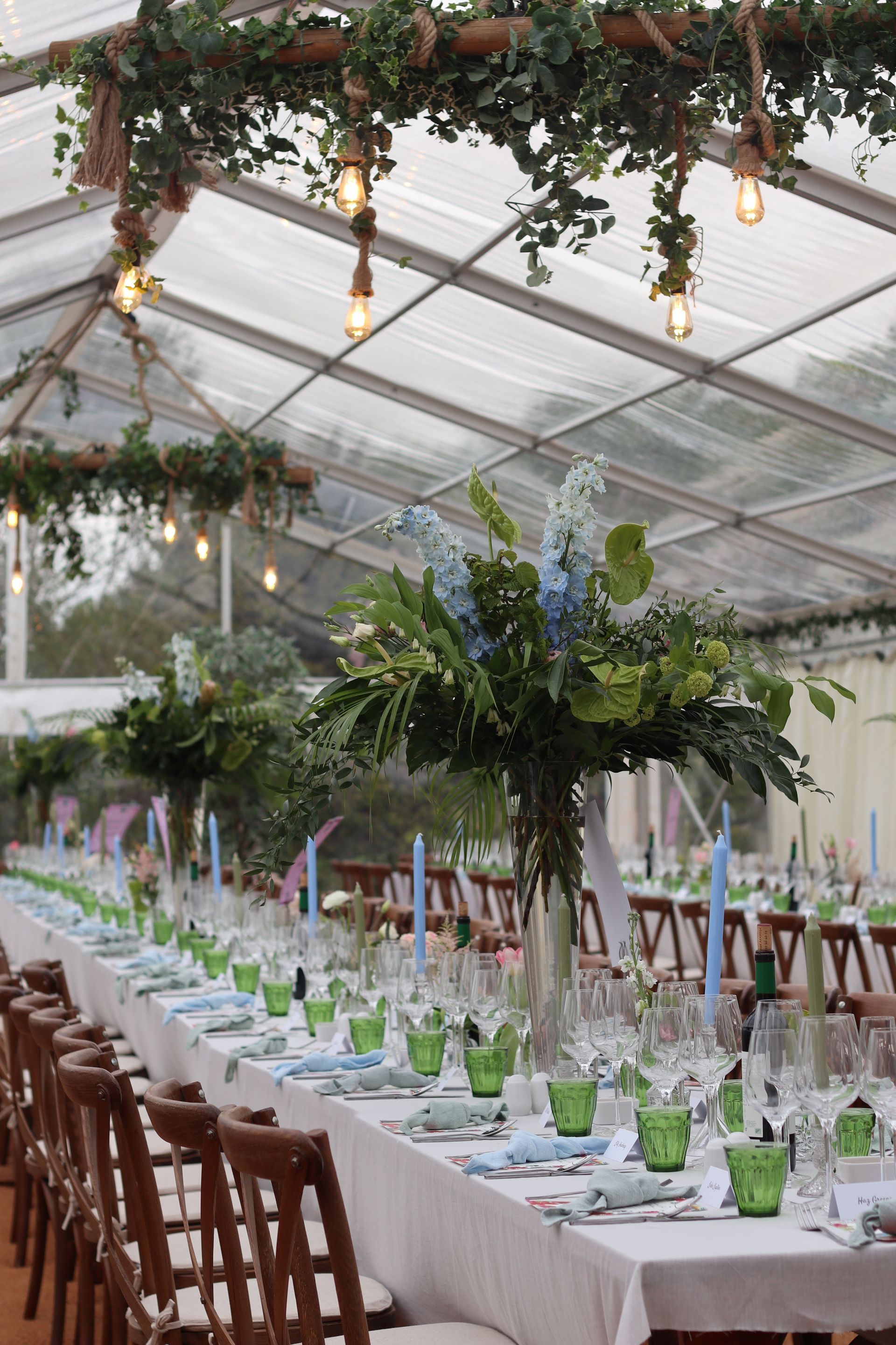 A long table set for a wedding reception under a clear tent.