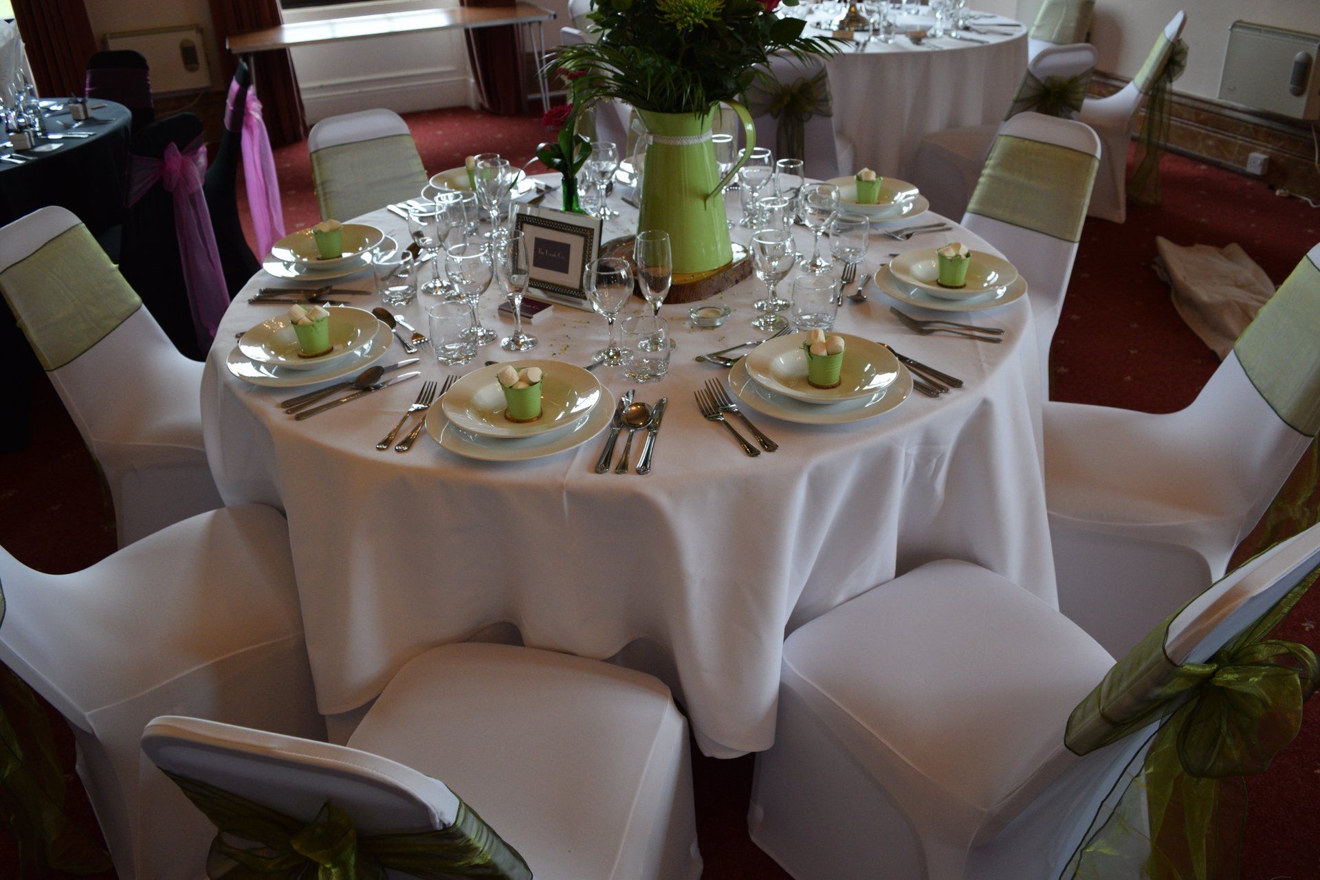 A table set for a wedding reception with a vase of flowers on it