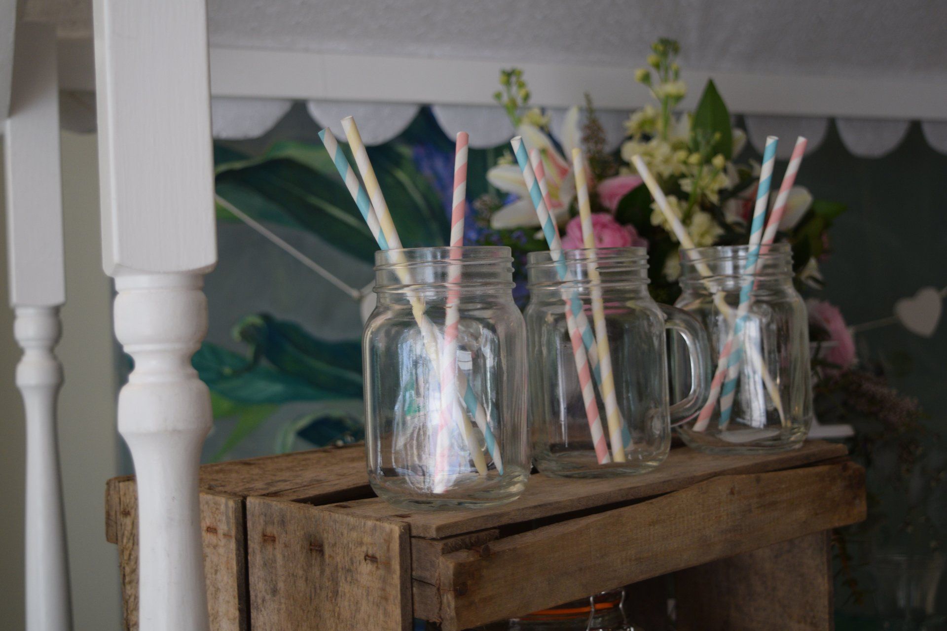 Mason jars filled with straws are sitting on a wooden crate.