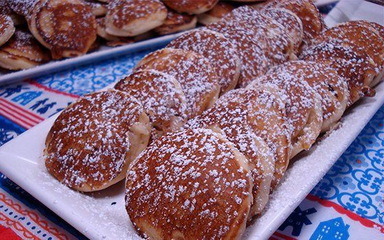 A white plate topped with pancakes covered in powdered sugar.