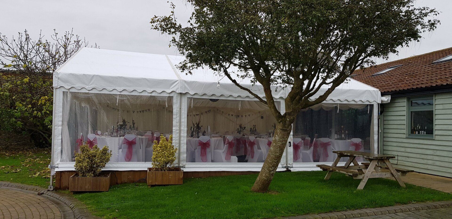 A white tent is sitting in the grass next to a tree.