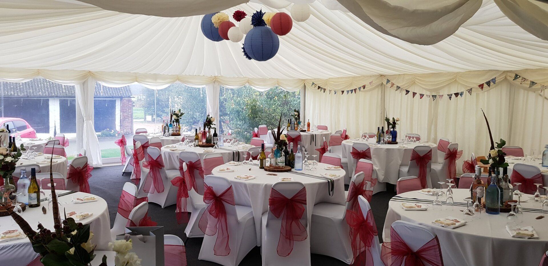 A large tent with tables and chairs set up for a wedding reception.