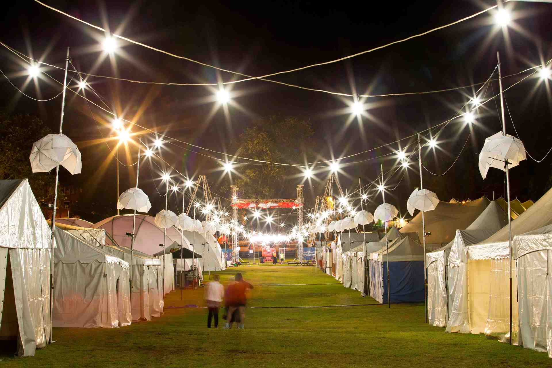 A row of tents are lit up at night