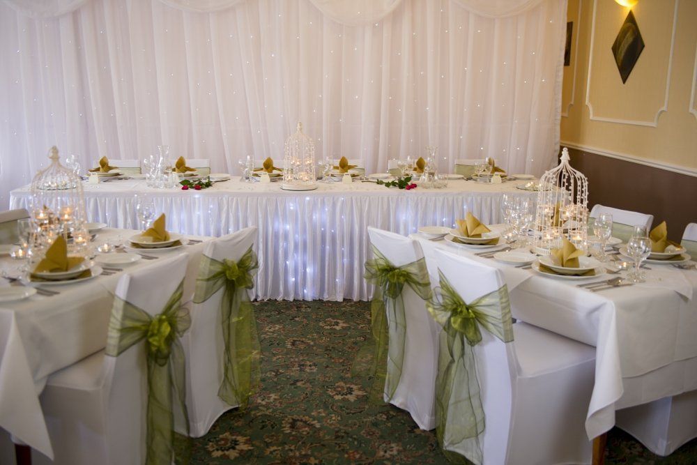 A room with tables and chairs set up for a wedding reception.