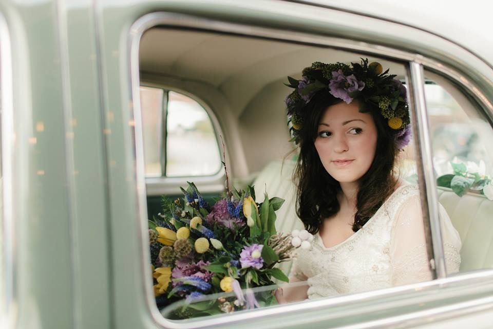 The bride is wearing a flower crown and holding a bouquet of flowers.