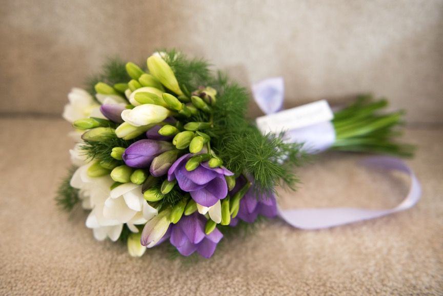 A bouquet of white and purple flowers is sitting on a couch.