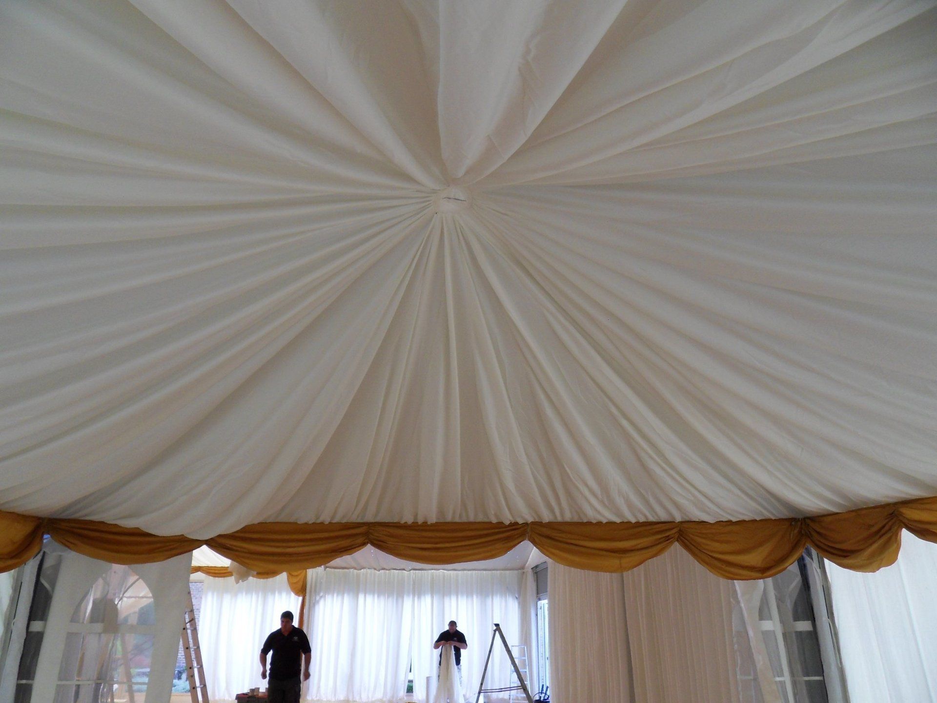 A man is standing under a white tent with gold trim.