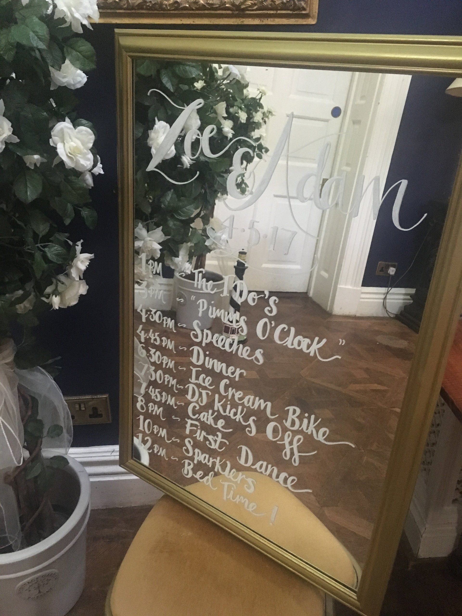 An ornate mirror with a wedding reception time line written on it