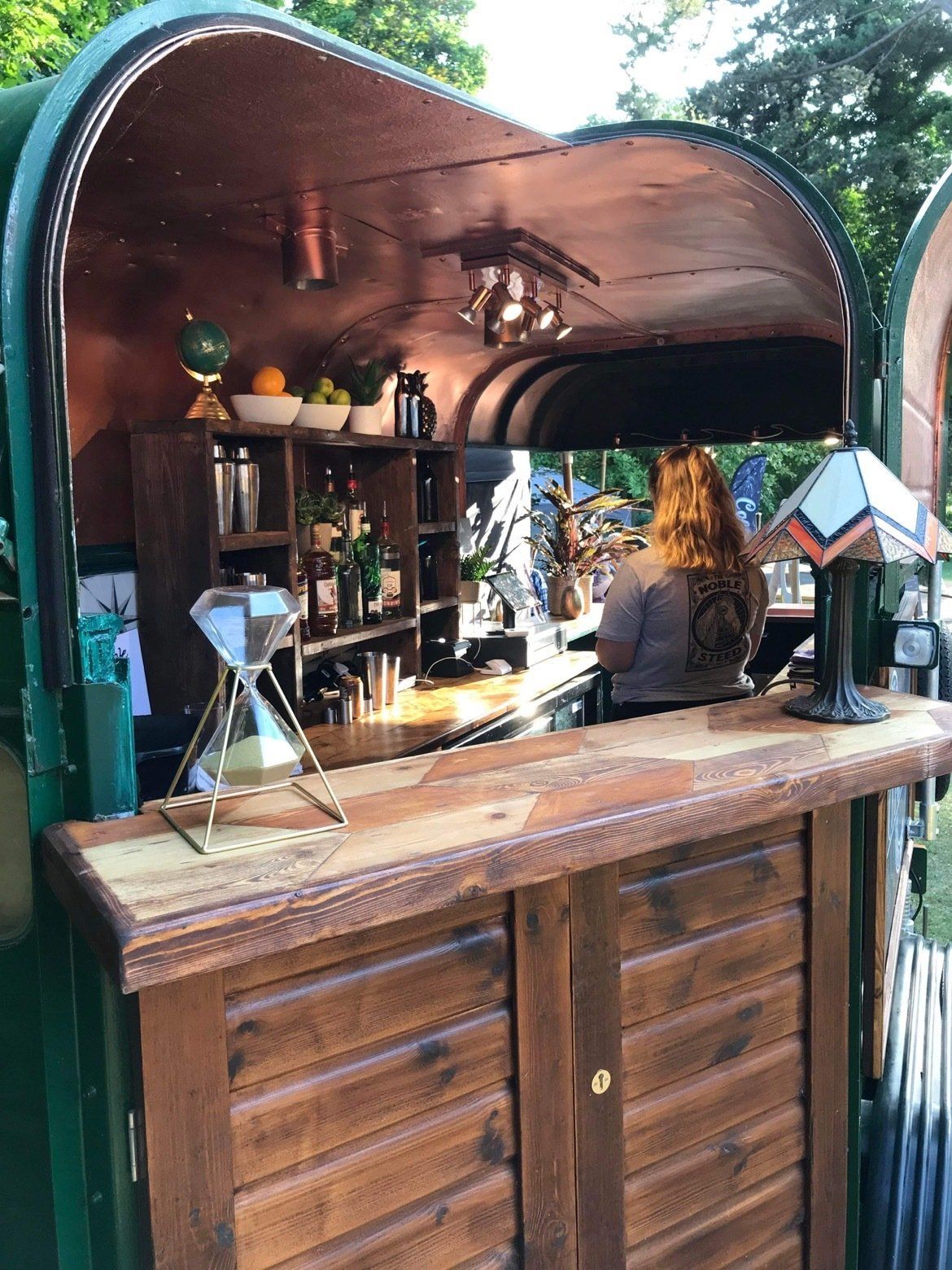 A woman is sitting at a wooden bar in a trailer.