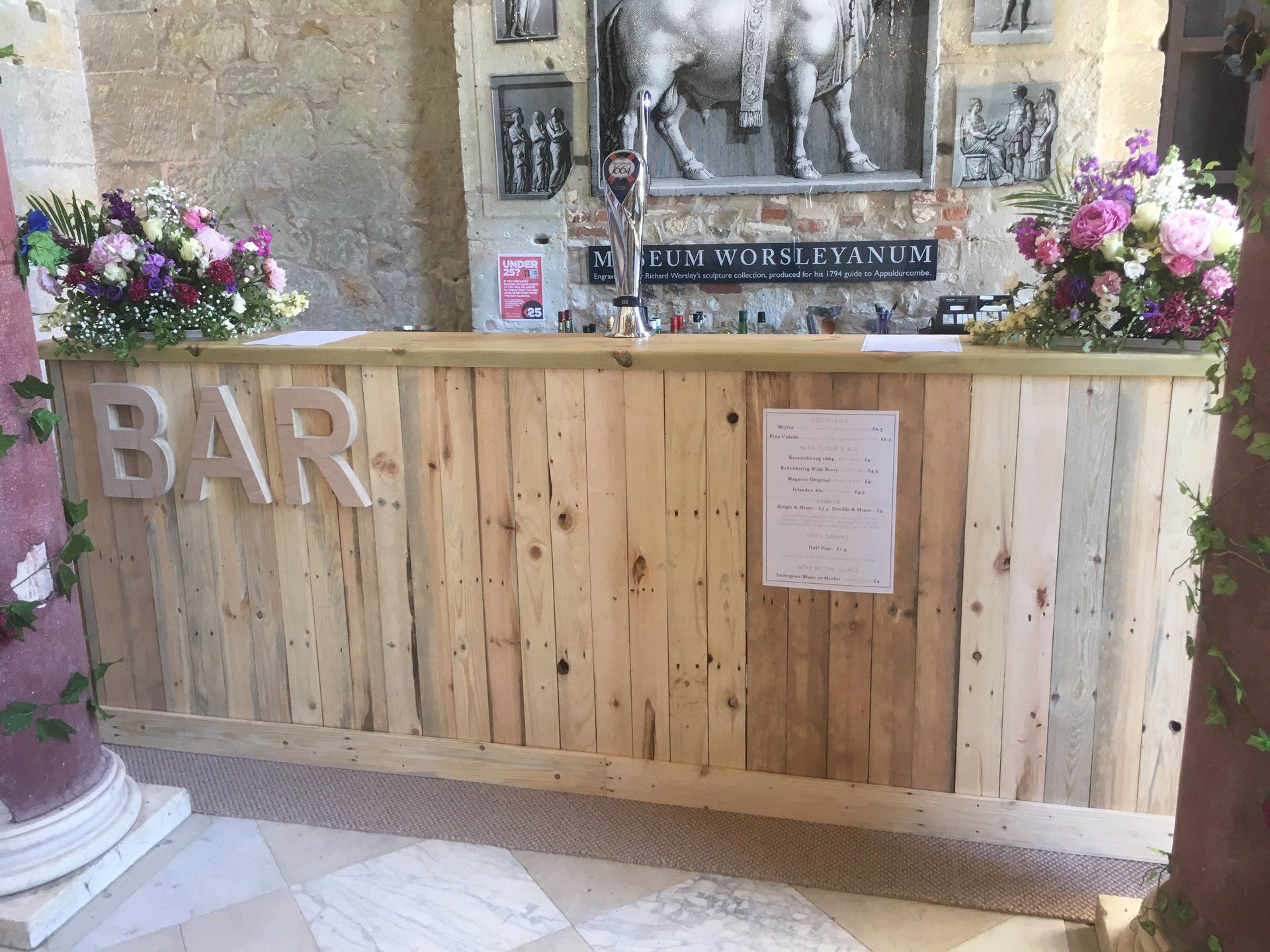 A wooden bar with flowers on top of it in a room.