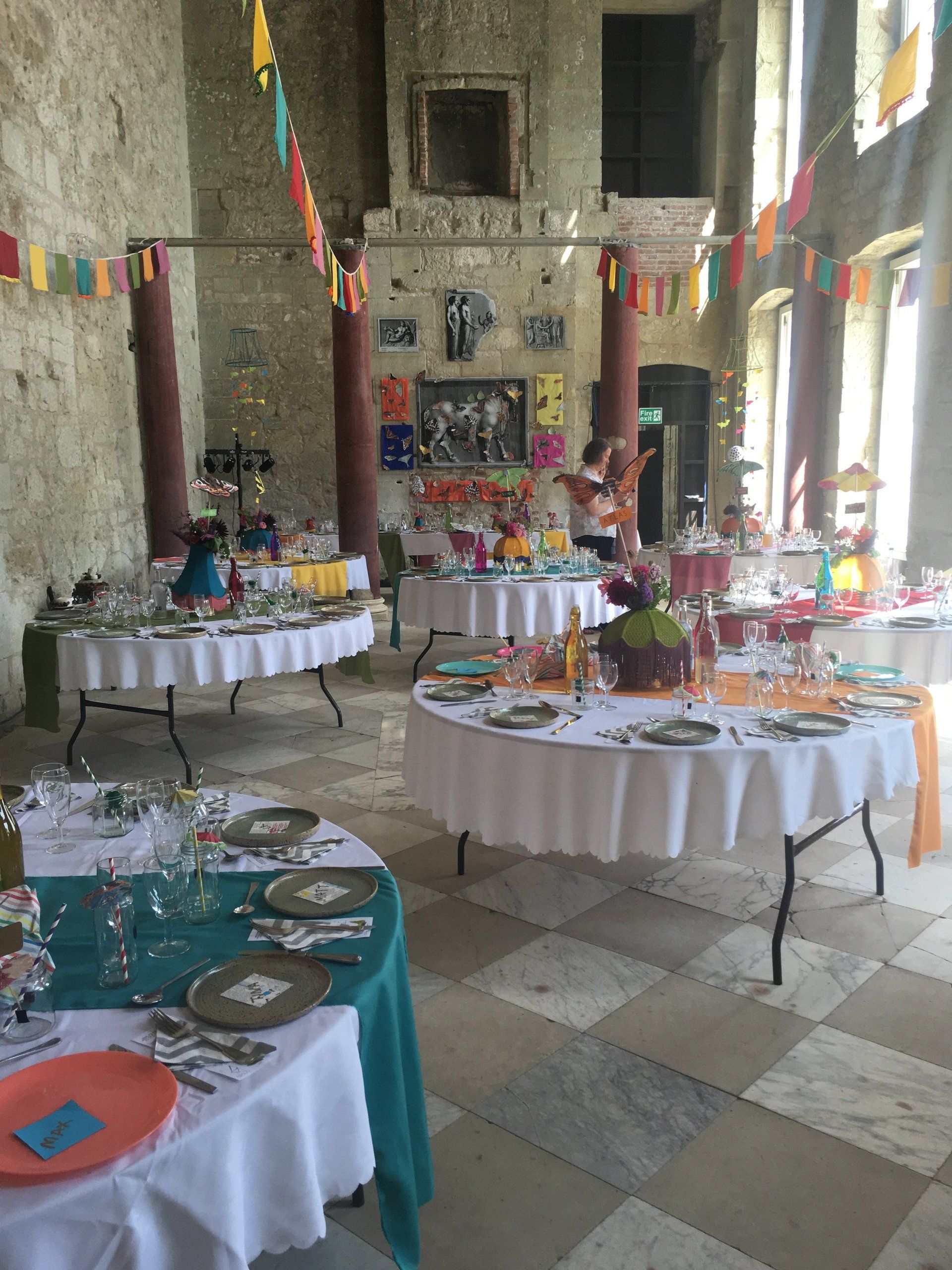 A large room with tables and plates set up for a party
