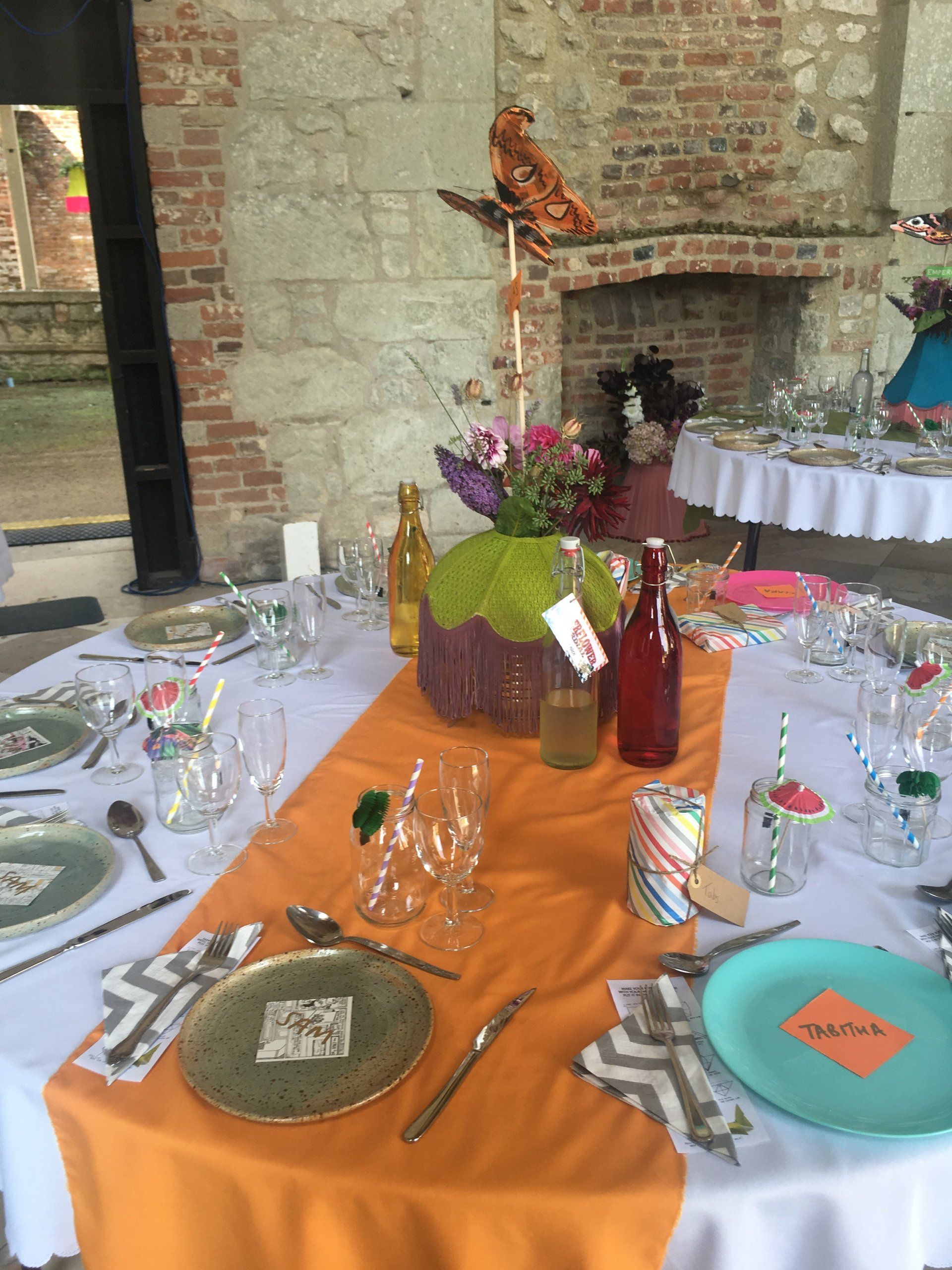 A table with plates , utensils and a vase of flowers on it