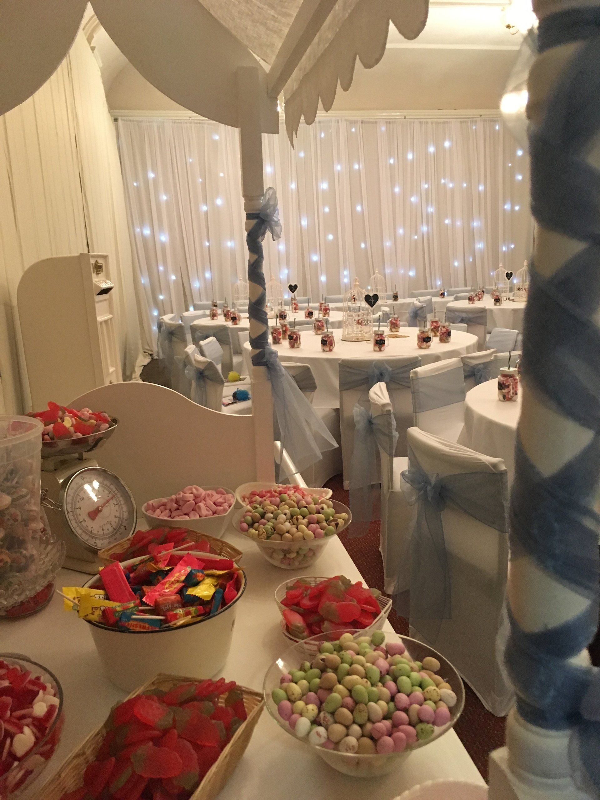A table with bowls of candy on it in a room with tables and chairs.