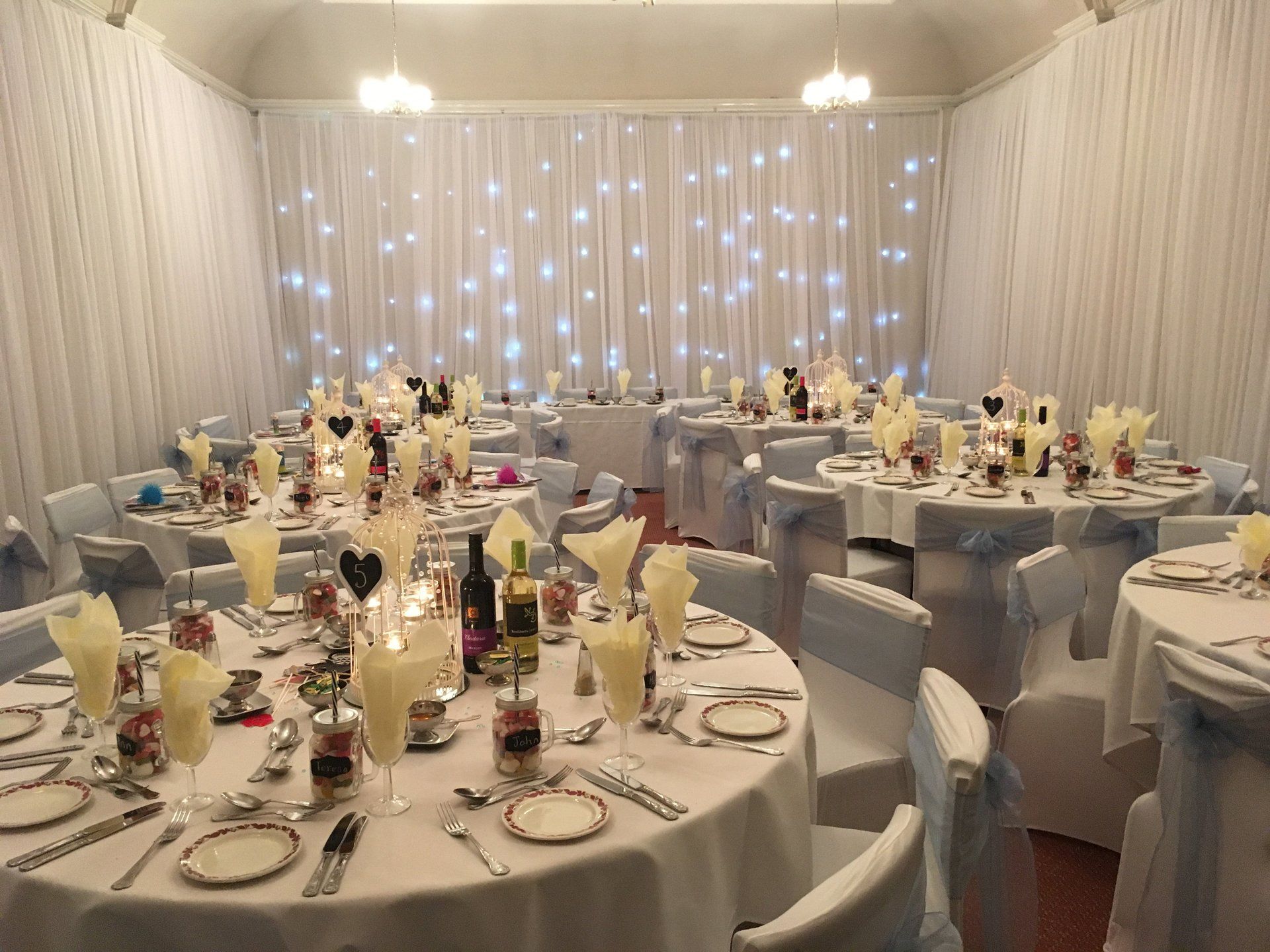 A large room with tables and chairs set up for a wedding reception.