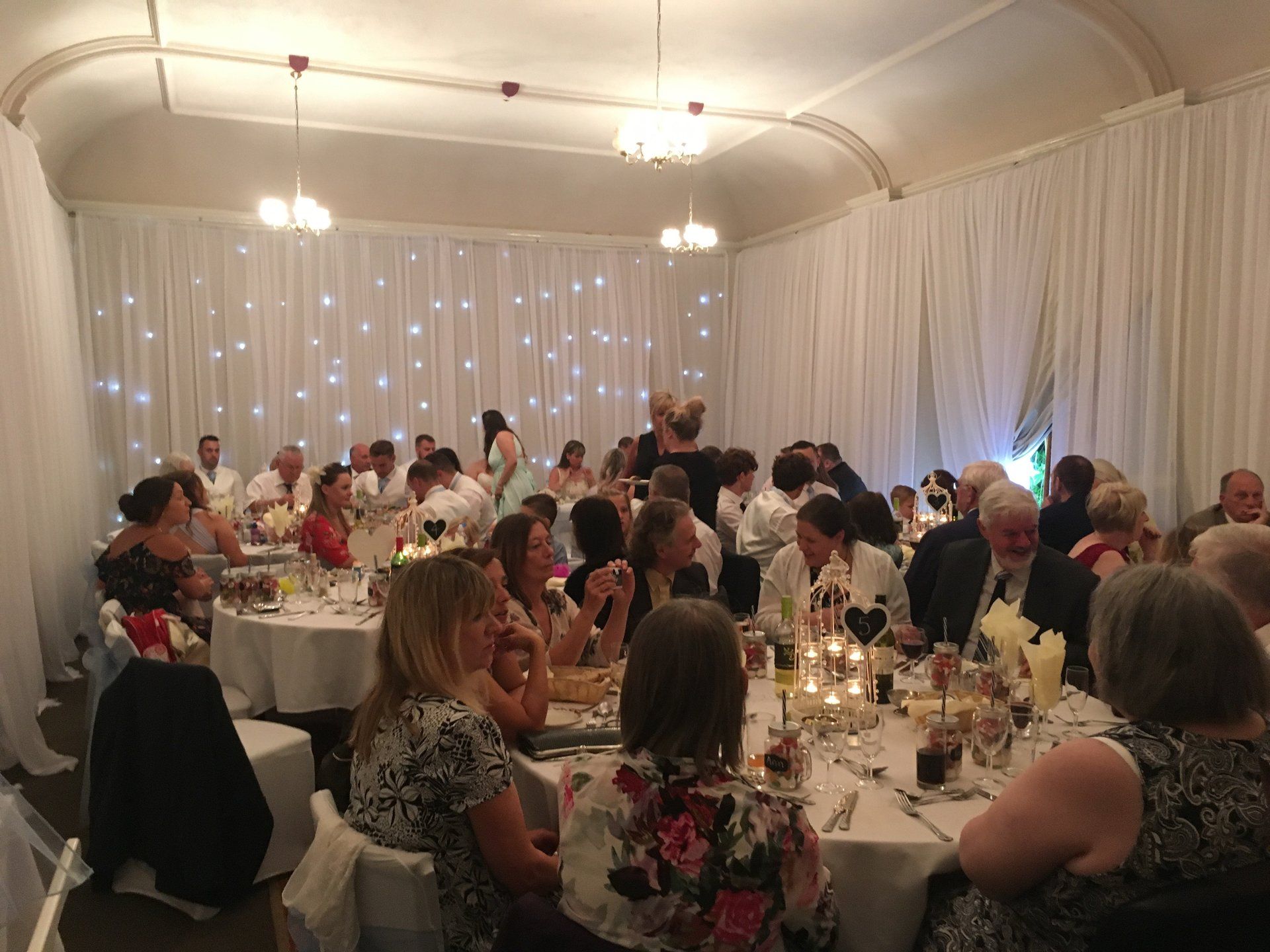 A large group of people are sitting at tables at a wedding reception.