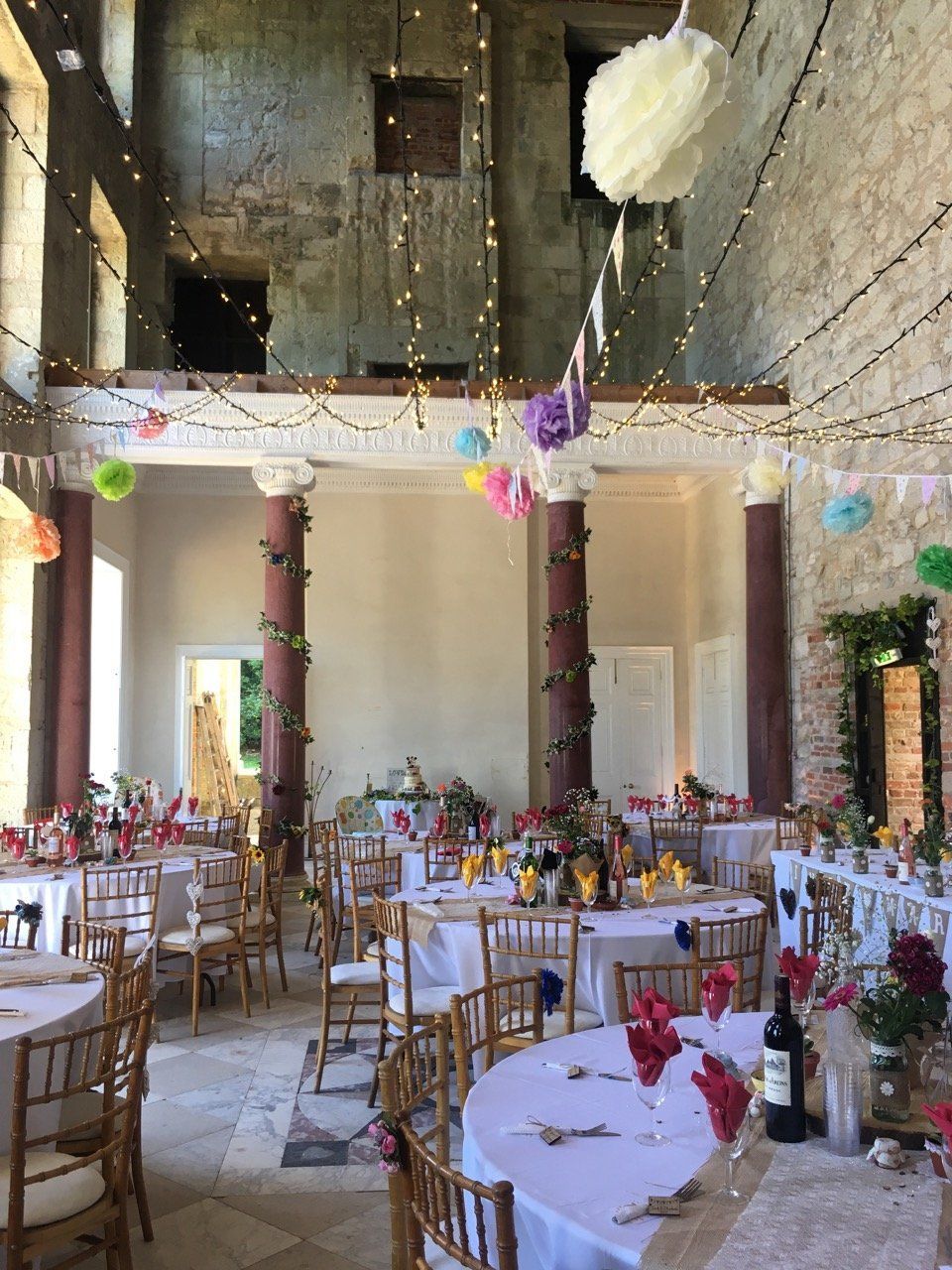 A large room with tables and chairs set up for a wedding reception.
