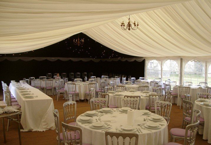 A large tent with tables and chairs set up for a wedding reception