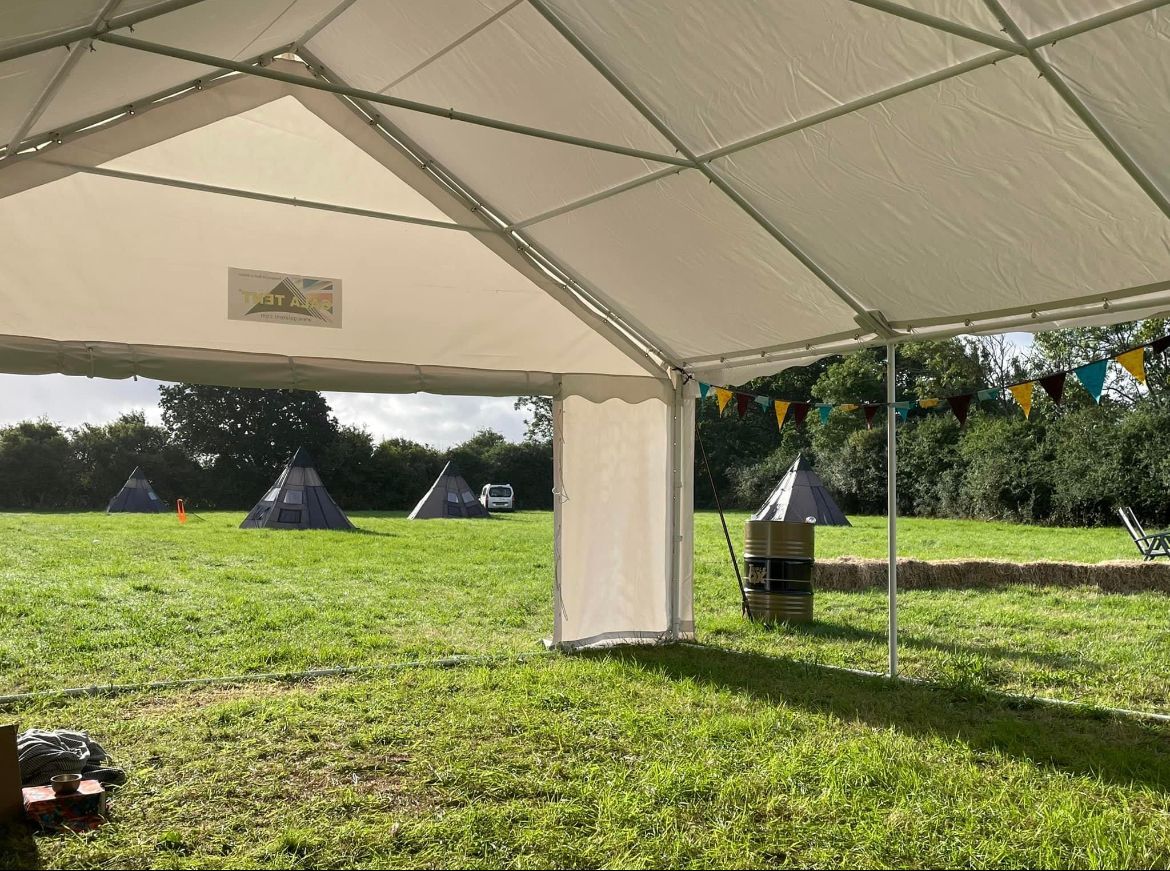 A white tent is sitting in the middle of a grassy field.