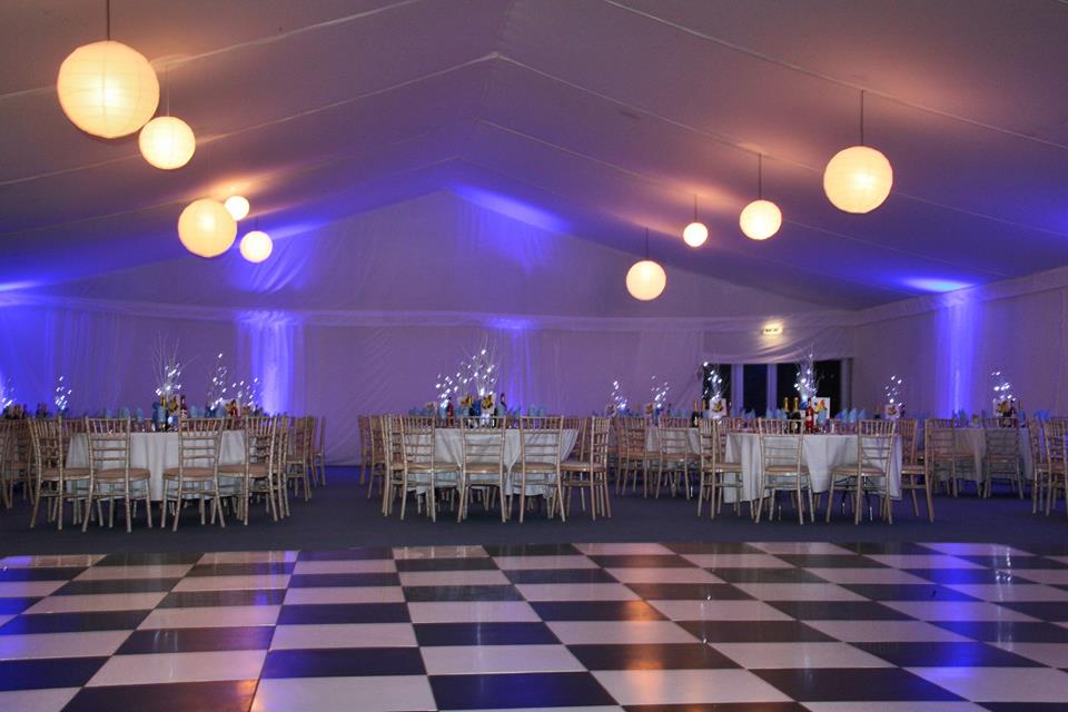 A large room with tables and chairs and a checkered dance floor.