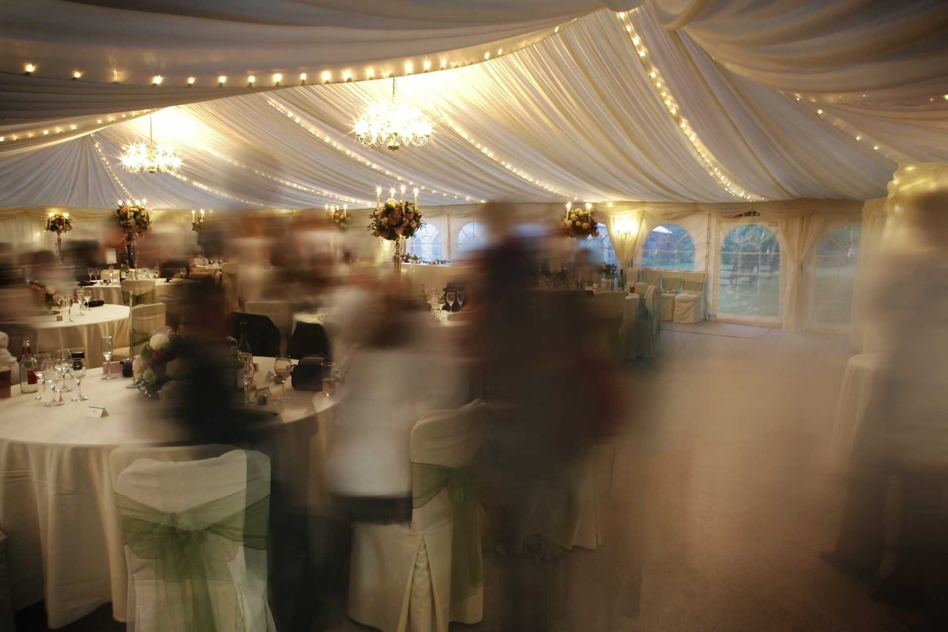 A blurry picture of people dancing in a tent at a wedding reception.