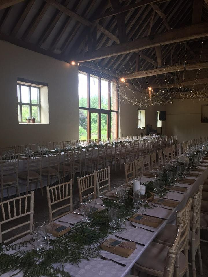 A large room with tables and chairs set up for a wedding reception