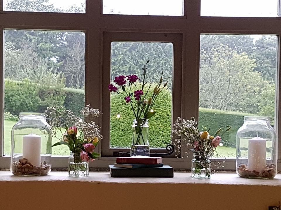 A window sill with vases of flowers and candles on it