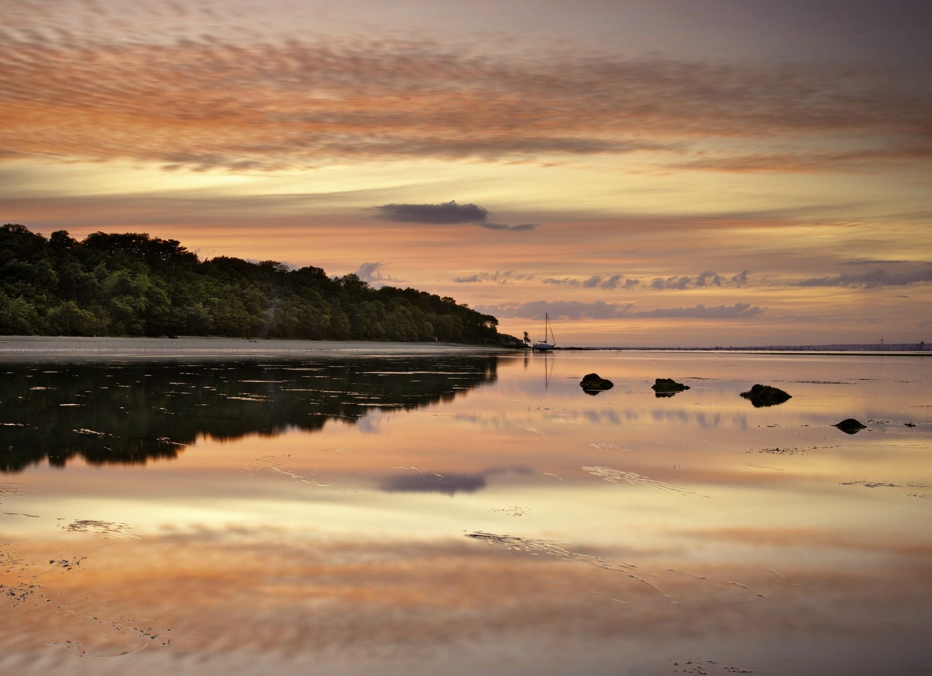 A sunset over a body of water with trees in the background