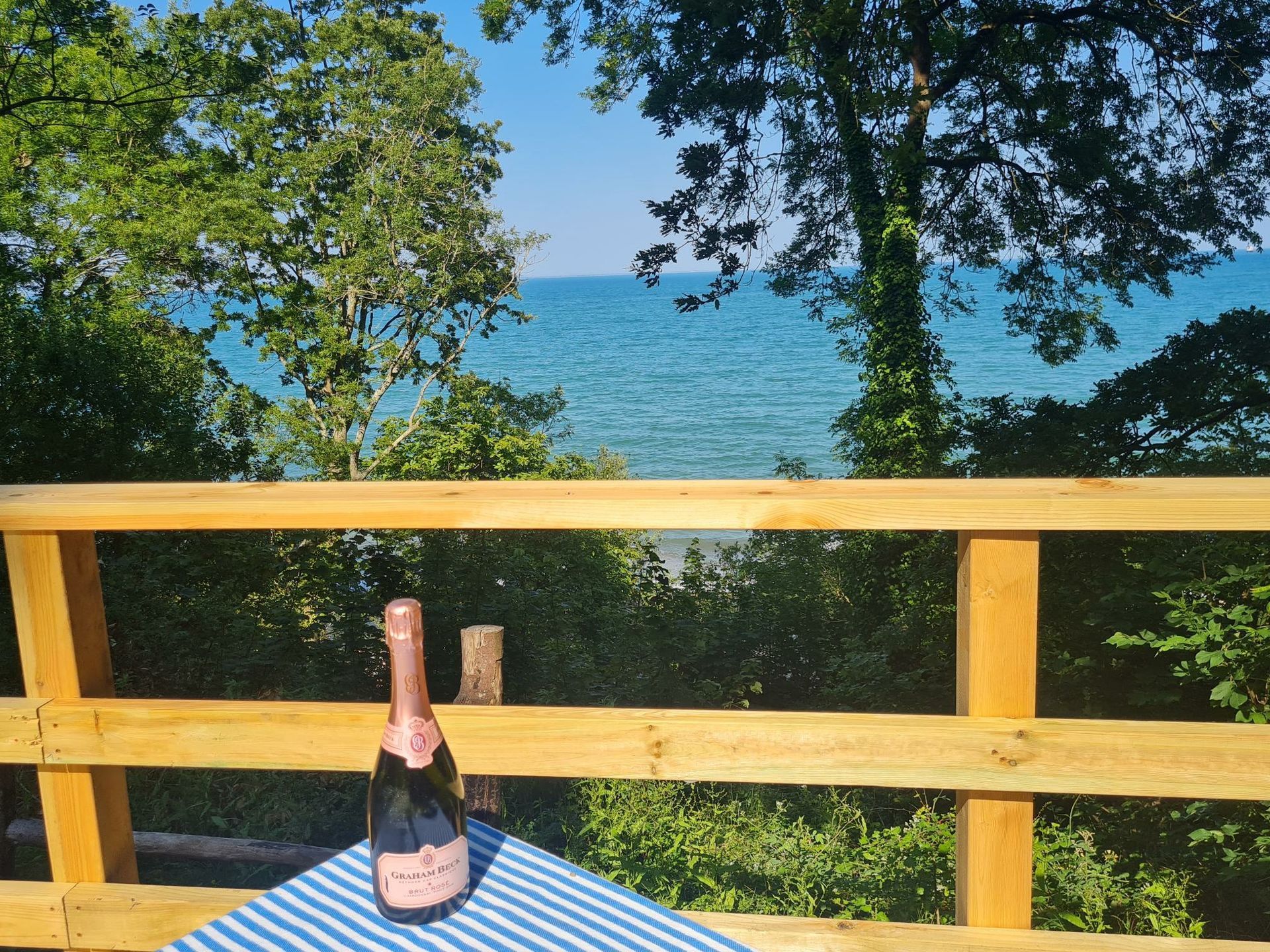 A bottle of champagne sits on a table overlooking the ocean