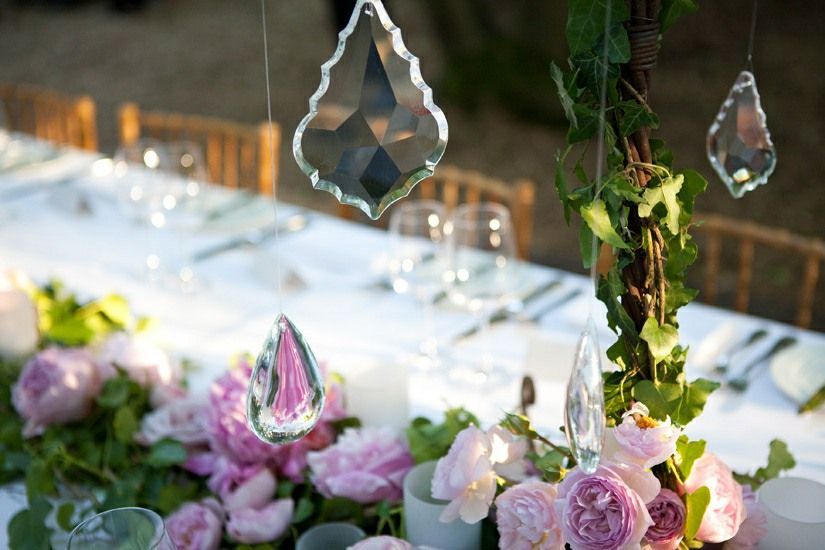 A long table with flowers and crystals hanging from it
