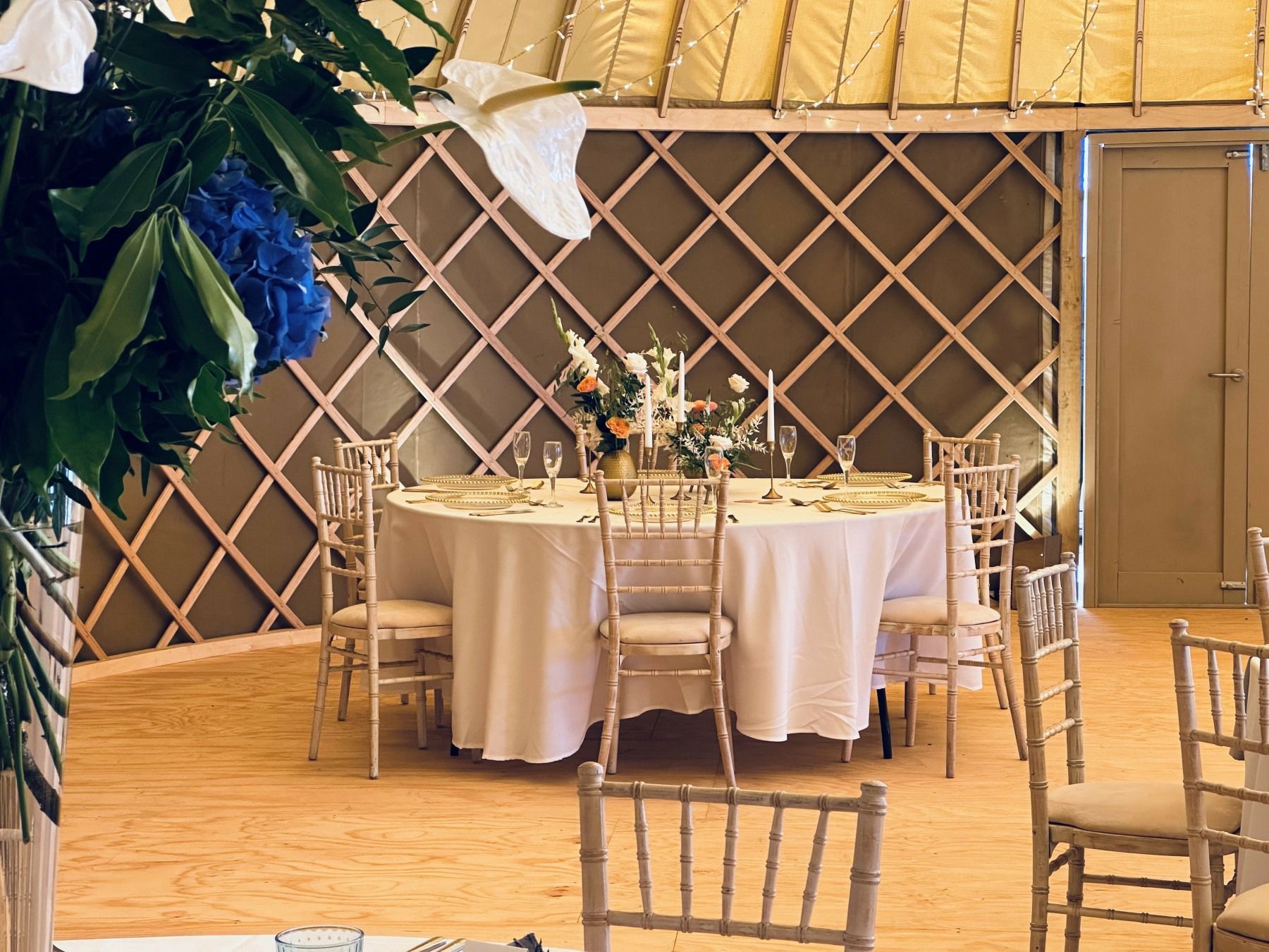 A room with tables and chairs set up for a wedding reception.