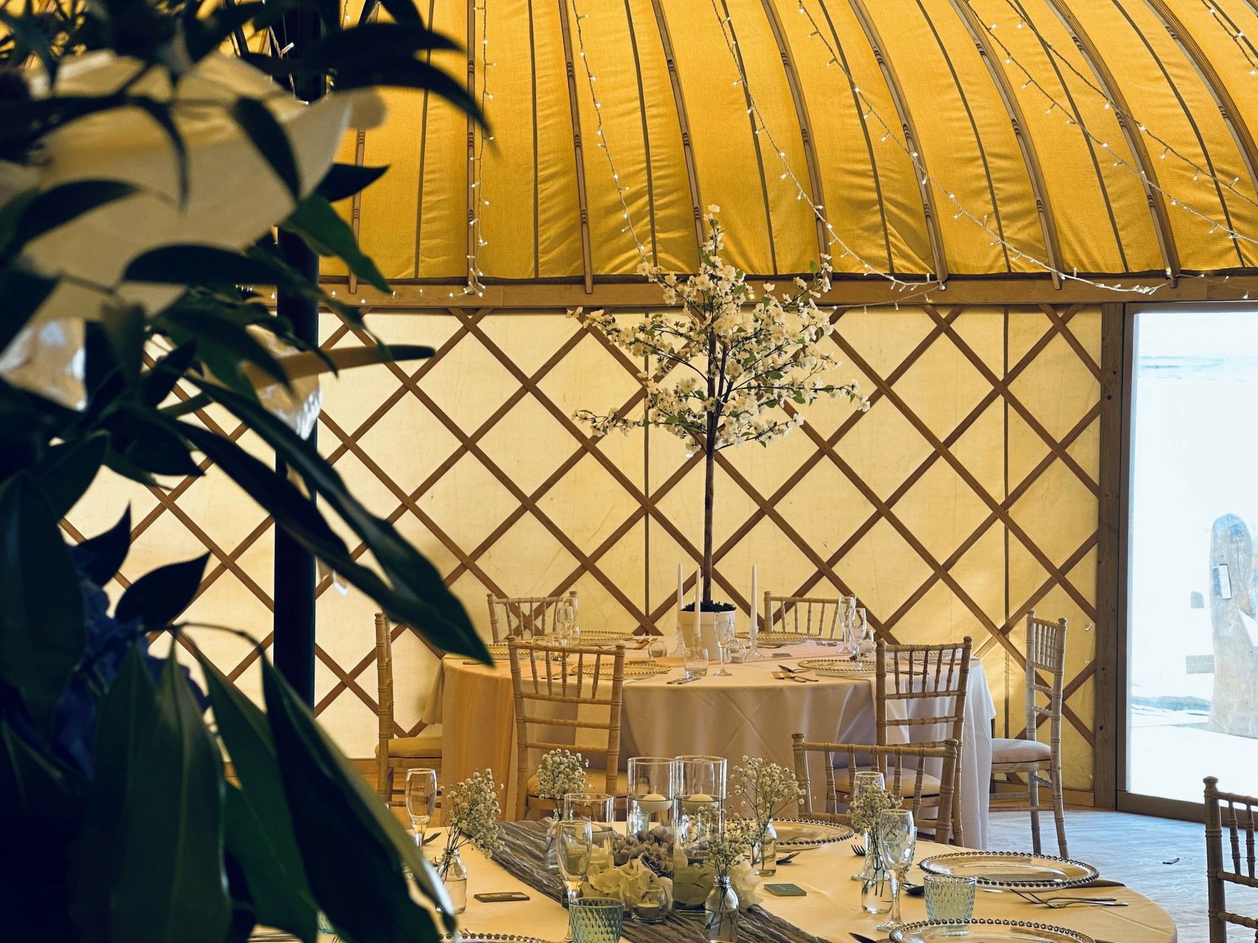 A room with tables and chairs set up for a wedding reception.
