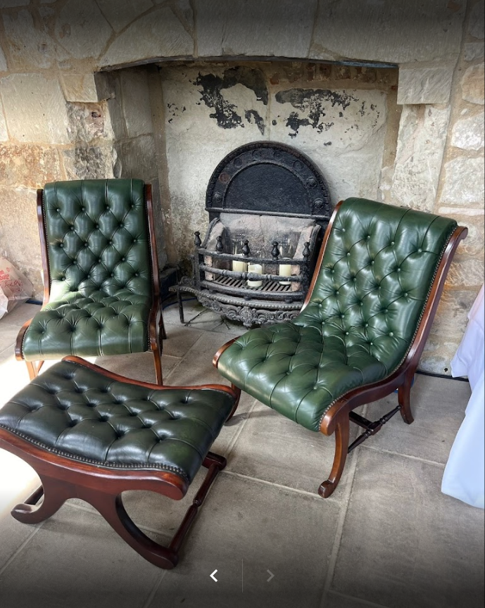 Two green leather chairs and an ottoman are sitting in front of a fireplace.