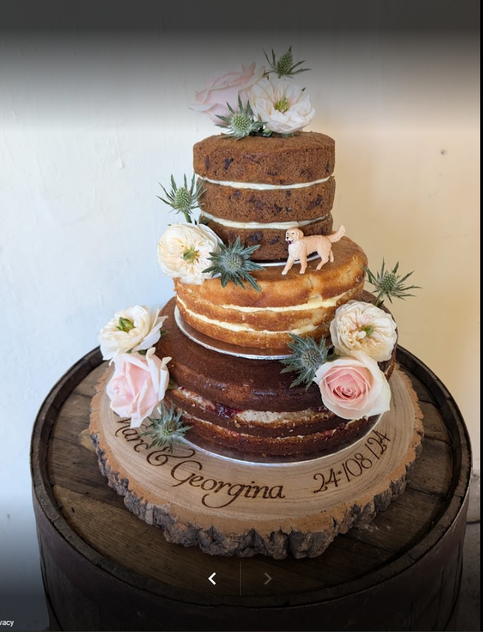 A wedding cake is sitting on top of a wooden barrel.