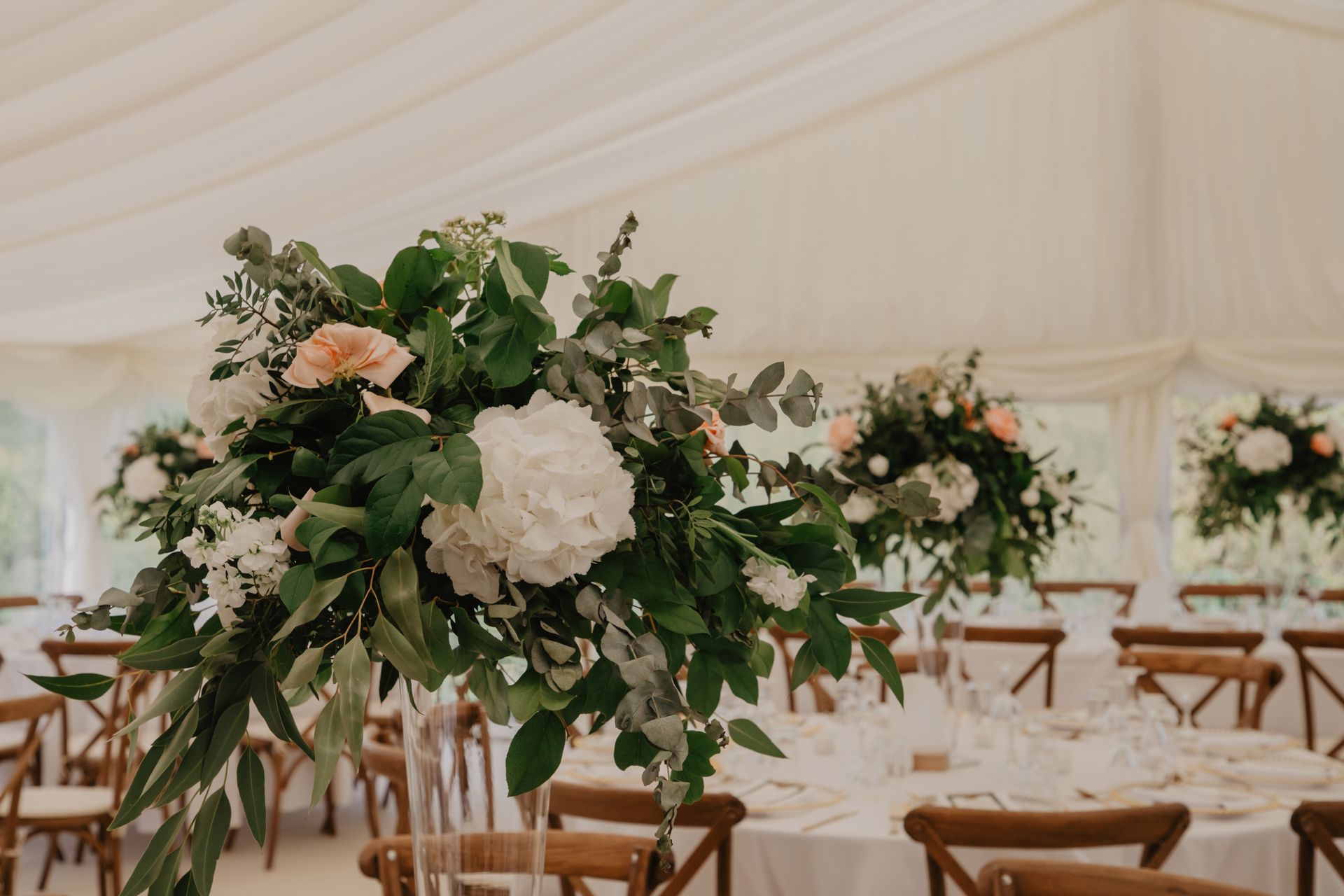 A large bouquet of flowers is sitting on a table in a tent.