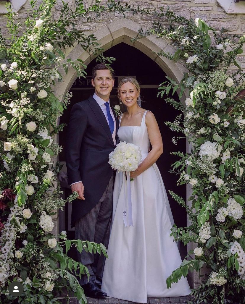 A bride and groom are posing for a picture in front of a church.