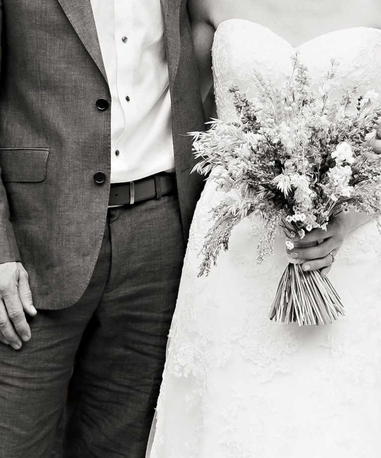 A black and white photo of a bride and groom holding hands