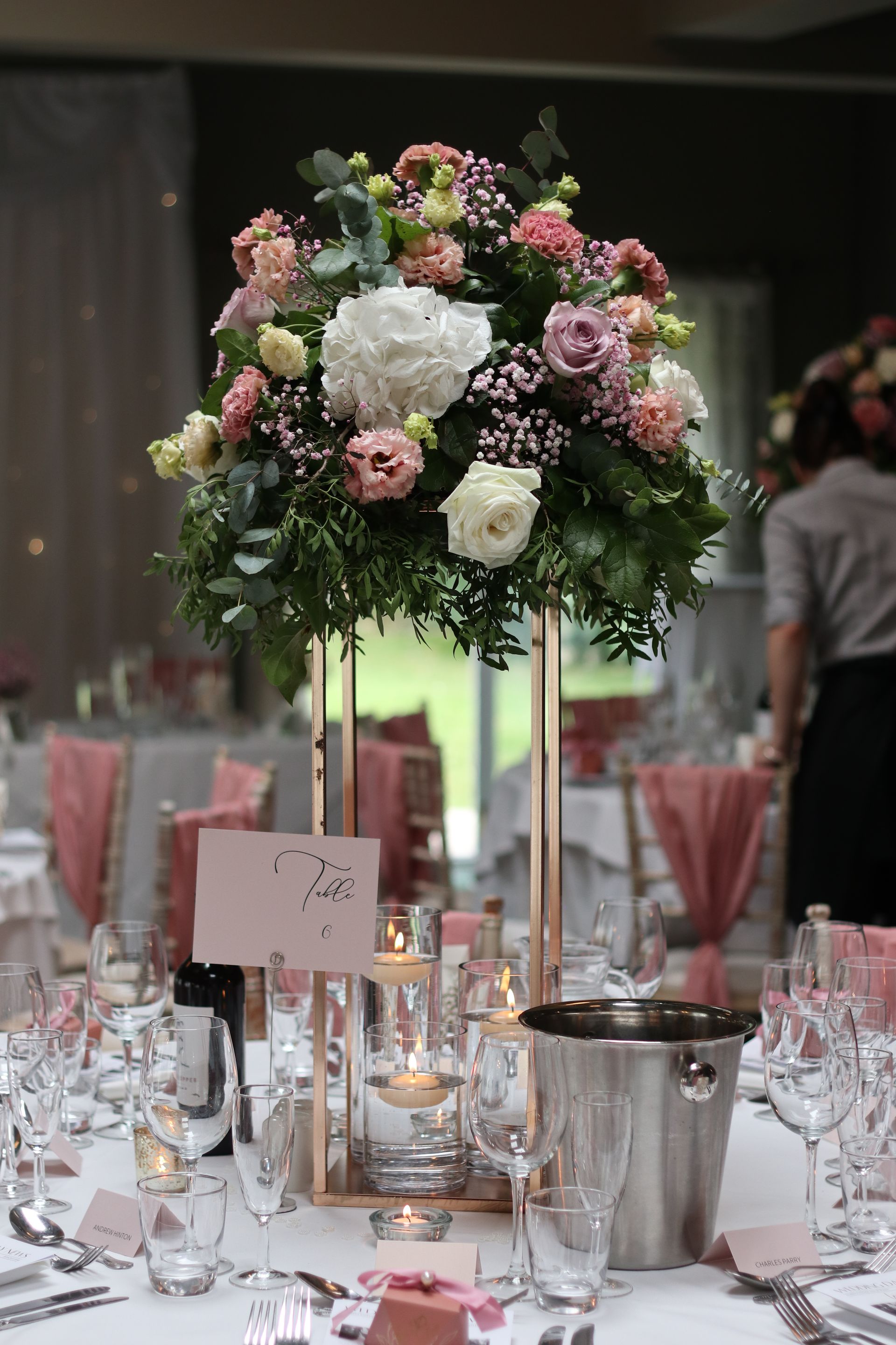 A table set for a wedding reception with a vase of flowers on it.
